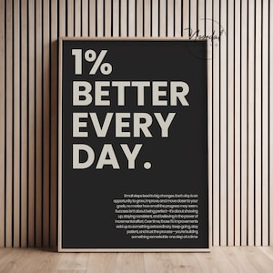 A black framed print with large beige typography that reads 1% better every day and a smaller motivational paragraph below.
