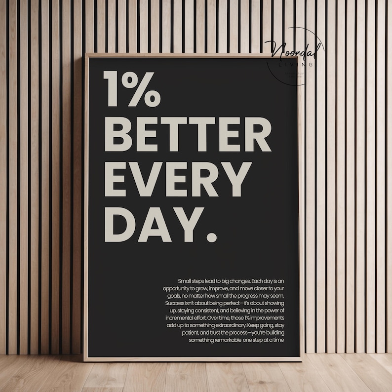 A black framed print with large beige typography that reads 1% better every day and a smaller motivational paragraph below.