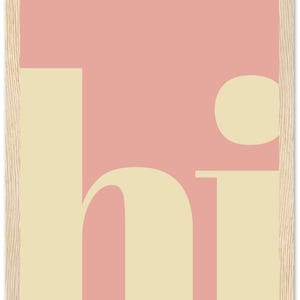 May include: A framed art print with a minimalist design. The artwork features the word "hi" in a soft, cream-colored font against a pink background. The frame is made of light-colored wood, adding a natural touch.