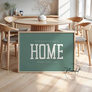 May include: A framed teal print with the word "HOME" in white block letters. Below the word "HOME" are the names Julien, Nico, and Lisa. The print is in a light wood frame and is displayed in a dining room setting.