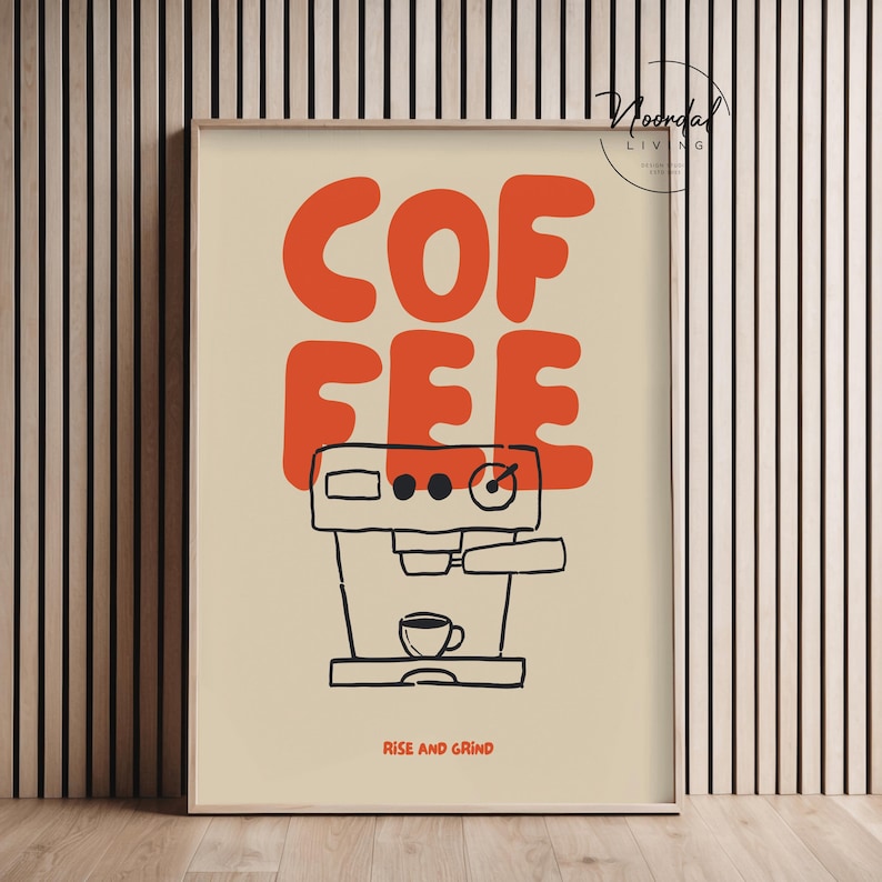 May include: A framed art print with a coffee theme. The word "COFFEE" is in large orange letters above a black and white illustration of an espresso machine. The phrase "RISE AND GRIND" is printed in black at the bottom.