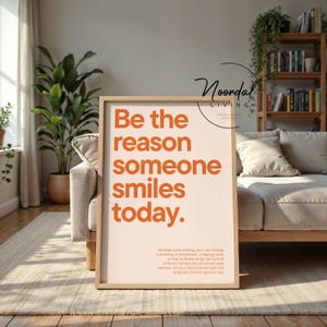 Könnte beinhalten: Ein rechteckiges gerahmtes Wandbild mit hellbeigem Hintergrund und fettgedrucktem orangefarbenem Text, der lautet: Be the reason someone smiles today. Darunter befindet sich ein kleinerer orangefarbener Textabschnitt über Freundlichkeit.