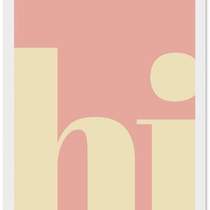 May include: A minimalist art print featuring the word "hi" in a soft, cream-colored font against a muted pink background. The design is simple, with a modern aesthetic, and is framed in white.