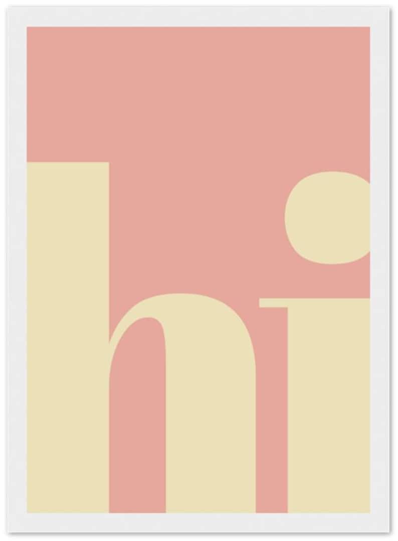 May include: A minimalist art print featuring the word "hi" in a soft, cream-colored font against a muted pink background. The design is simple, with a modern aesthetic, and is framed in white.