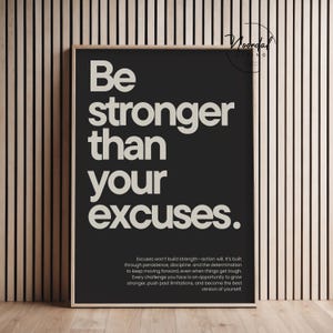 Könnte beinhalten: Gerahmtes schwarz-weißes Motivationsposter mit dem Text "Be stronger than your excuses." Das Poster enthält einen Absatz über den Aufbau von Stärke durch Ausdauer und Entschlossenheit. Der Rahmen ist hellholzfarben.