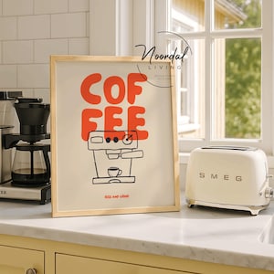 May include: A framed art print with the word "COFFEE" in red block letters and a black line drawing of a coffee machine. The phrase "RISE AND GRIND" is below the drawing. A cream-colored toaster is to the right.