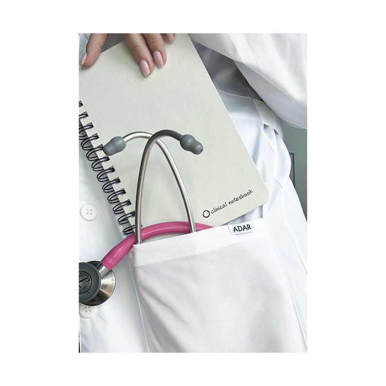 Może przedstawiać: Biały fartuch laboratoryjny z kieszenią, w kt&oacute;rej znajduje się r&oacute;żowy stetoskop i notes w spirali z napisem "Clinical Notebook" i "ADAR" na okładce.