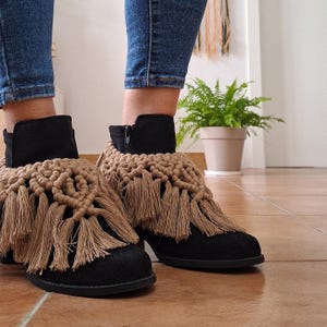Op de afbeelding: Zwarte enkellaarsjes met bruine gecrochete franjes. De franjes zijn gemaakt van een dikke, natuurlijke vezel en hangen tot aan de enkel.