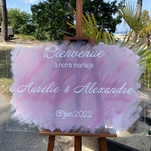 Peut inclure: Une pancarte de mariage en acrylique rose et blanche avec le texte "Bienvenue à notre mariage", "Aurélie & Alexandre" et "13 juin 2022".