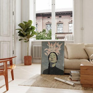 May include: A painting of a woman with pink feathers on her head, she is wearing a black turtleneck and has her eyes closed. The painting is on a canvas and is framed in a gold frame.