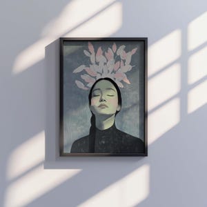 May include: A framed illustration of a woman with closed eyes and a serene expression. Pink and white stylized leaves are arranged above her head. The background is a soft blue-green color.