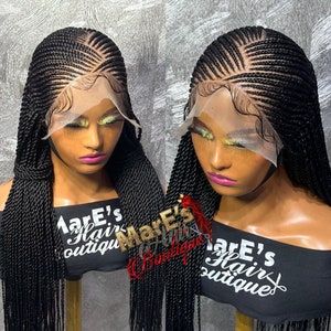 Puede incluir: Dos pelucas trenzadas negras con un frente de encaje en soportes para pelucas. Las pelucas están diseñadas con un patrón de trenzas africanas con trenzas largas y rectas. Las pelucas están etiquetadas como "Mare's Hair Boutique".