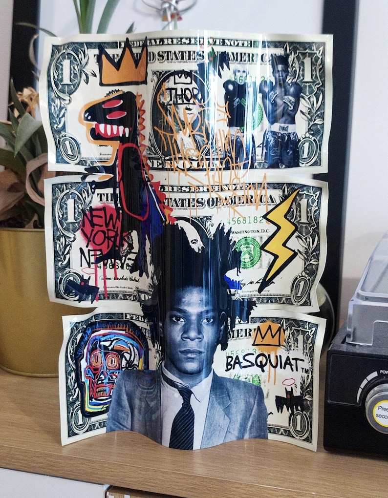 K&ouml;nnte beinhalten: Ein dreidimensionales Kunstwerk mit Dollarnoten mit Graffiti-Kunst und Portr&auml;ts. Das Kunstwerk enth&auml;lt Bilder eines Dinosauriers, einer Krone, eines Boxers und den Text "NEW YORK". Die untere Note zeigt ein Portr&auml;t von Jean-Michel Basquiat.