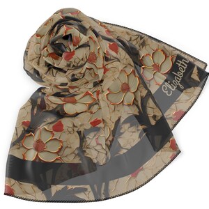 May include: A beige floral scarf with a repeating pattern of flowers in beige, red, and gold. The scarf has a black border with the name "Elizabeth" printed on it. The scarf is made of a sheer material.