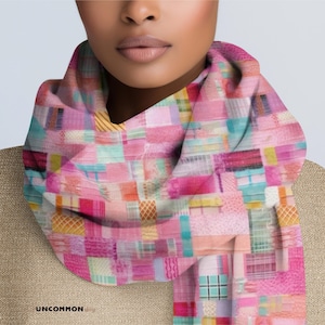 May include: A colorful scarf with a patchwork design. The scarf features a variety of pink, teal, yellow, and orange rectangular patterns. The scarf is wrapped around a person's neck.