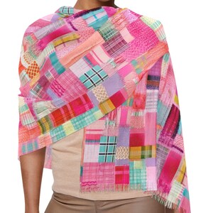 Puede incluir: Bufanda de retazos colorida en tonos rosa, rojo, naranja y azul. La bufanda está drapeada, mostrando diversos patrones y texturas de tela. Los bordes están deshilachados.