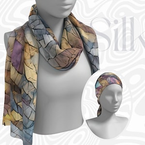 May include: A silk scarf and headscarf set. The scarf is draped around a mannequin, displaying a mosaic-like pattern in shades of blue, purple, and tan. The headscarf, also with the mosaic design, is displayed on a separate mannequin head.