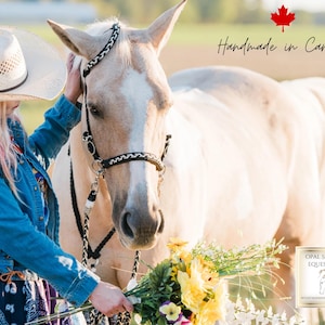 Op de afbeelding: Een palominopaard met een zwart-wit gevlochten halster. Een persoon met een strohoed en een spijkerjasje aait het paard. De afbeelding bevat de tekst "Handmade in Canada" en "Opal Summer Equestrian".