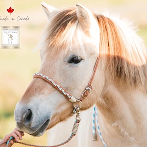 Puede incluir: Un caballo de color claro con un cabestro trenzado y una cuerda a juego. La imagen incluye el texto "Handmade in Canada" y un logotipo de Opal Summer Equestrian. El caballo está siendo sujetado por una persona.