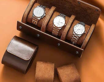 May include: A brown leather watch box with four slots for storing watches. The box has a velvet lining and is closed with a metal clasp. The box is sitting on a brown surface.