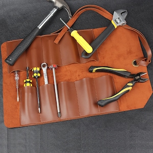 May include: A brown leather tool roll containing a selection of tools, including a hammer, wrench, pliers, and screwdrivers.
