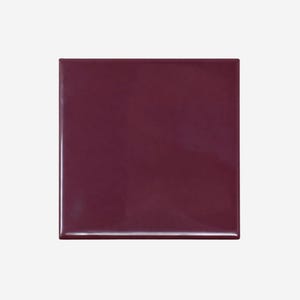 May include: A square, burgundy-colored tile with a glossy finish. The tile is a solid color and appears to be made of ceramic or a similar material. The edges are clean and well-defined, suggesting a high-quality product.