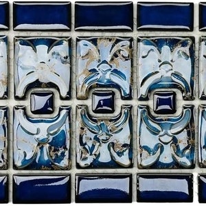 May include: A close-up of a blue and white mosaic tile sheet with a decorative floral pattern. The tiles are arranged in a grid pattern and have a glossy finish.