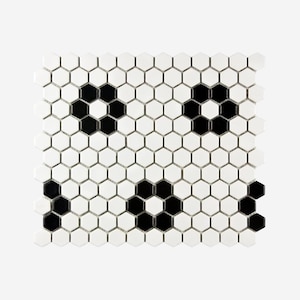 May include: A square mosaic tile sheet composed of white and black hexagonal tiles. The black tiles are arranged in a floral pattern, creating a contrasting design against the white background. The tiles are likely ceramic or porcelain.