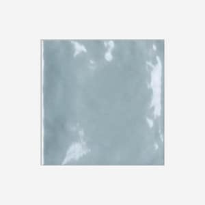May include: Square, light blue ceramic tile with a glossy finish. The tile has a slightly irregular surface, with subtle variations in color and texture. The edges are clean and straight, and the overall appearance is modern and minimalist. Ideal for home decor.