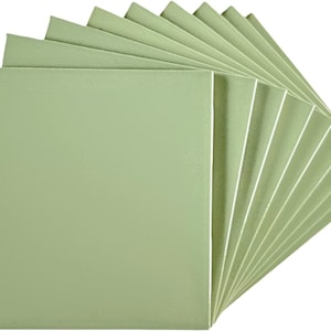 May include: A stack of 12 light green square tiles. The tiles are arranged in a fan shape.