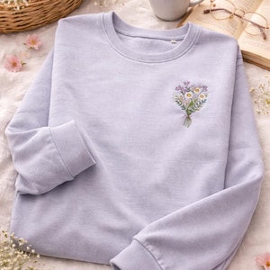 May include: A white ceramic mug with a black handle and the text "But First, Coffee" in a black, handwritten-style font. The mug is on a white surface.