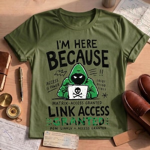 May include: An olive green t-shirt featuring a graphic of a hooded figure at a laptop with a skull icon. The text reads: I'M HERE BECAUSE ACCESS IS POWER, MATRIX-ACCESS GRANTED, LINK ACCESS GRANTED, and POM LINKLV ACCESS GRANTED with binary code.