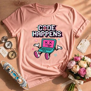 Könnte beinhalten: Ein pfirsichfarbenes Kurzarm-T-Shirt mit einer Grafik eines blauen Laptops mit rosa Bildschirm, X-förmigen Augen und herausgestreckter Zunge. Der Text "CODE HAPPENS" steht darüber in einer schwarzen, verpixelten Glitch-Schriftart.
