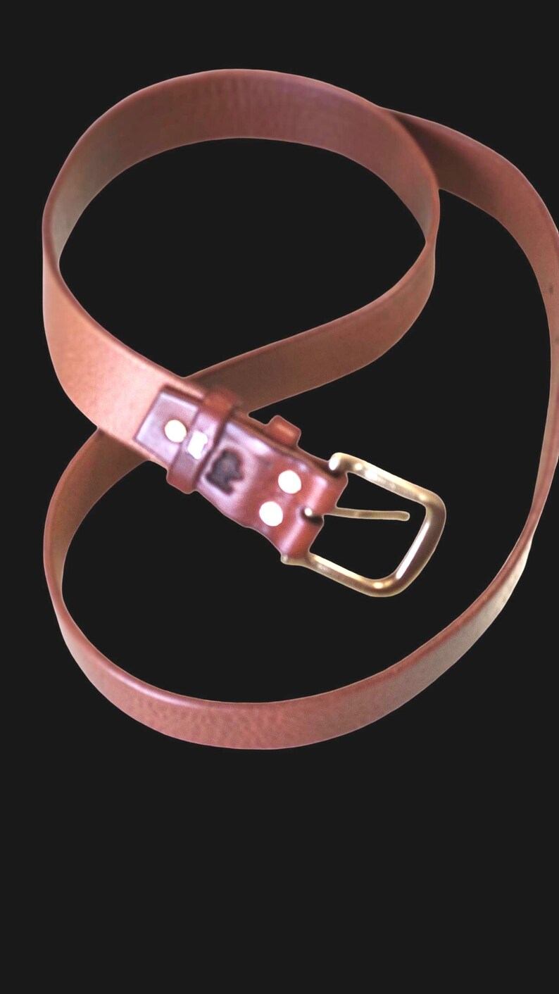 Peut inclure: Une ceinture en cuir marron avec une boucle en laiton. La ceinture est de couleur marron moyen et poss&egrave;de une boucle rectangulaire. La ceinture est incurv&eacute;e et semble neuve.