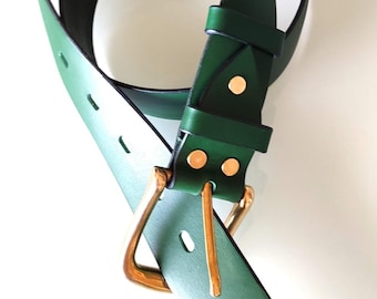 Puede incluir: Un cinturón de cuero verde con una hebilla dorada. El cinturón tiene un acabado liso y pulido y está doblado por la mitad.