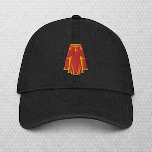 May include: A black baseball cap with a red and yellow embroidered design of a cape.