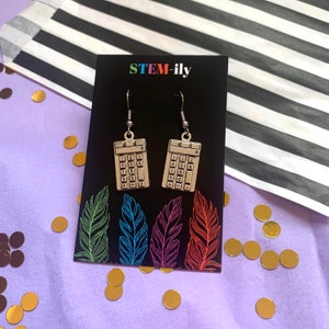 May include: A pair of silver calculator earrings with a black background and the text "STEM-ily".