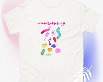 May include: White t-shirt with the text "meowcrobiology" in pink script. The shirt features colorful illustrations of various microorganisms, including pink, blue, green, and yellow shapes. The design is centered on the front of the shirt.