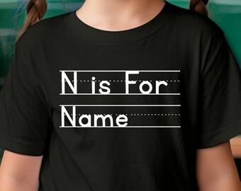 May include: A black t-shirt with white text that says "N is for Name". The shirt is being worn by a young person with pigtails and glasses.