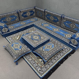 May include: A blue and white patterned floor cushion set with a traditional Moroccan design. The set includes a large L-shaped sofa, four smaller cushions, and a square coffee table. The cushions are all made of a soft, plush fabric and are perfect for lounging.
