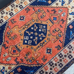 May include: A close-up of a colourful rug with a geometric pattern. The rug is made of wool and has a variety of colours, including red, orange, blue, and brown.