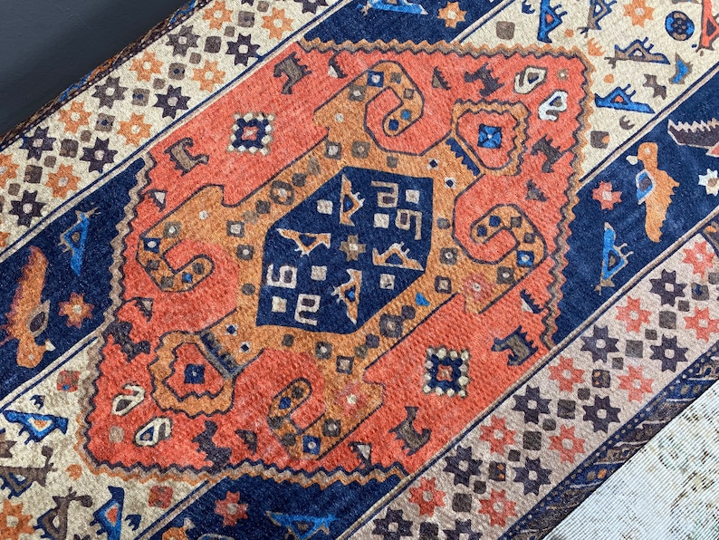 May include: A close-up of a colourful rug with a geometric pattern. The rug is made of wool and has a variety of colours, including red, orange, blue, and brown.