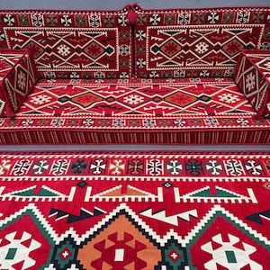 May include: A red and green patterned floor cushion set with a matching rug. The cushions are made of a soft, plush fabric and are perfect for lounging or sitting on the floor. The rug is made of a durable material and is easy to clean.