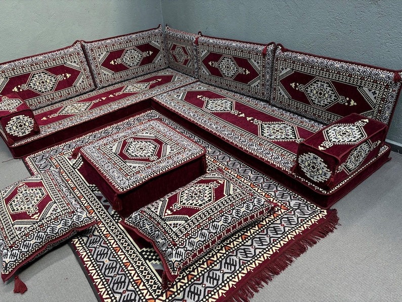 Pu&ograve; includere: Un set di sedute tradizionale marocchino con un tessuto a motivi bordeaux e crema. Il set comprende un grande divano angolare, diversi cuscini pi&ugrave; piccoli e un pouf quadrato. I cuscini e il pouf sono tutti rivestiti dello stesso tessuto del divano.