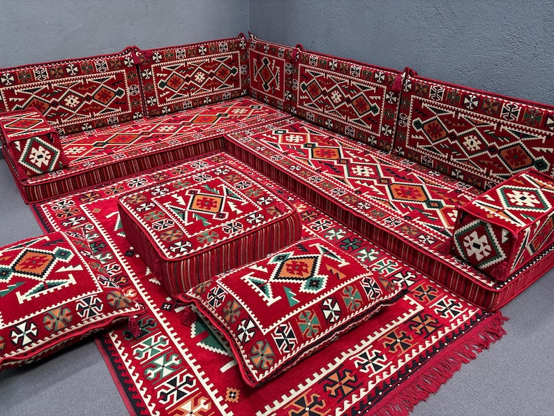 May include: A traditional red and white patterned floor seating set with cushions and pillows. The set includes a large sofa, smaller individual seats, and a square ottoman.