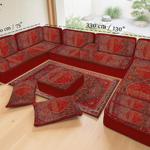 May include: A U-shaped seating set with a red base and patterned cushions. The set includes a sofa, ottoman, rug, and pillows. The sofa measures 130 inches long and 75 inches wide. The pillows and cushions have a red and brown pattern.