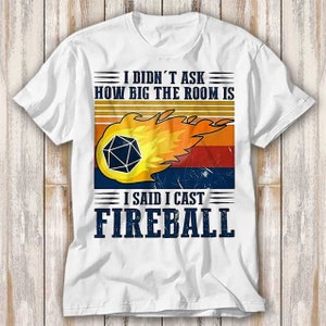 May include: White t-shirt with a retro-style graphic of a fireball with a dice inside. The text reads "I didn't ask how big the room is I said I cast FIREBALL".