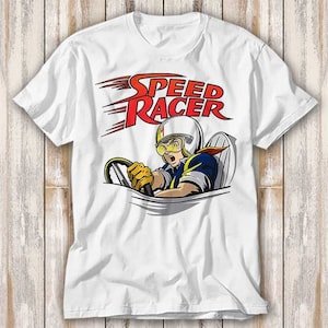 以下が含まれることがあります： 白いTシャツに、赤と黄色のスピードレーサーのグラフィックがプリントされています。グラフィックは、スピードレーサーが車を運転し、頭と肩が車から出ている様子を描いています。