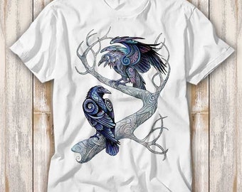 May include: White t-shirt with a graphic print of two blue and purple stylized ravens perched on a tree branch.