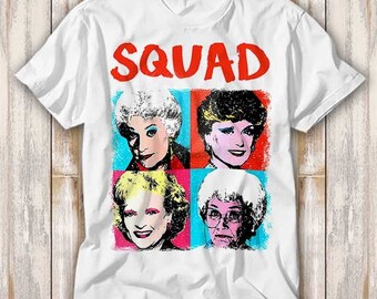 May include: White t-shirt with a red "SQUAD" graphic and four colorful pop art style images of women.
